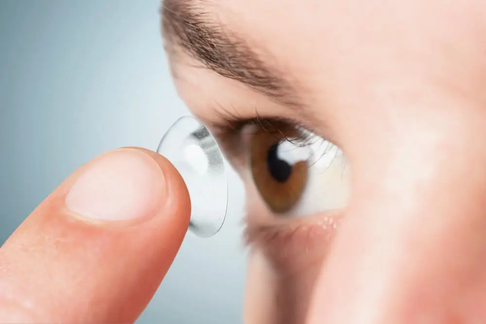 A person at Eye Pros is about to insert a contact lens into their eye.